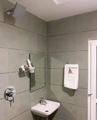 a bathroom with a sink and a mirror at New Thai Residency in Dhārāpuram