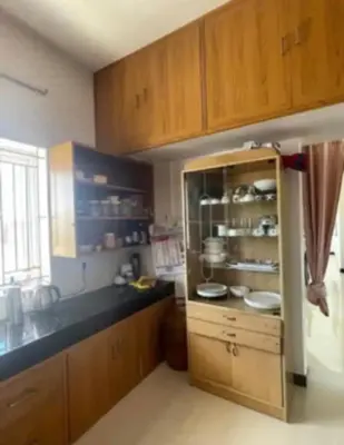 a kitchen with wooden cabinets and a counter top at White House Kotagiri, 2bhk in Kotagiri
