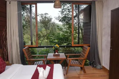 a room with a bed and a table and a window at TREE6 WAYANAD in Vythiri