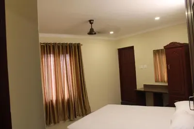 a bedroom with a bed and a window with curtains at LILLY RESIDENCY by Chungath in Perumbavoor