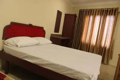 a bed with a red headboard and white pillows at LILLY RESIDENCY by Chungath in Perumbavoor