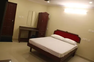 a bedroom with a bed and a dresser and a mirror at LILLY RESIDENCY by Chungath in Perumbavoor