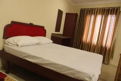 a bedroom with a bed with a red headboard and a window at LILLY RESIDENCY by Chungath in Perumbavoor