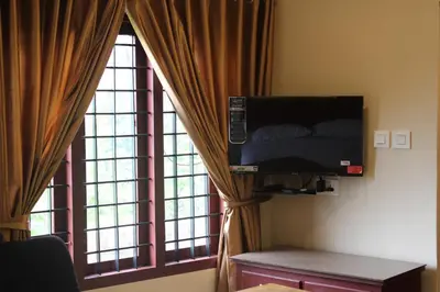 a room with a flat screen tv and two windows at LILLY RESIDENCY by Chungath in Perumbavoor