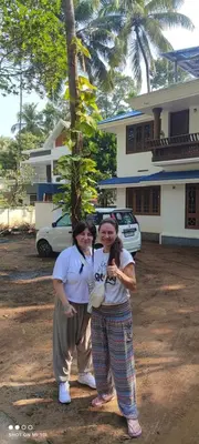 two women standing next to each other in front of a house at Vyshnavi Home stay in Thanniyam