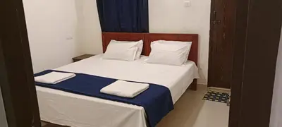 a bedroom with a bed with white and blue sheets at Vythiri Garden in Vythiri