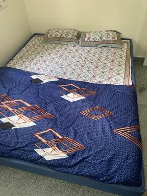 a bed with a blue blanket on top of it at Spacious 2BHK for upto 12 Guests , Best for Families & Groups in Mysore