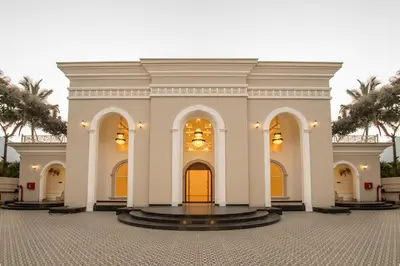 a large white building with yellow doors and palm trees at CSR Landmark Resorts in Coimbatore