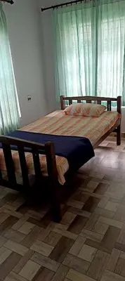 a large wooden bed in a bedroom with green curtains at JJ HOLIDAY HOMES WAYANAD in Kalpetta