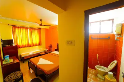 a room with a bedroom with two beds and a bathroom at AMOGHA RESIDENCY in Mysore