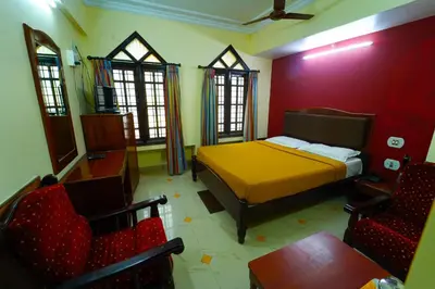 a bedroom with a bed and chairs in a room at AMOGHA RESIDENCY in Mysore