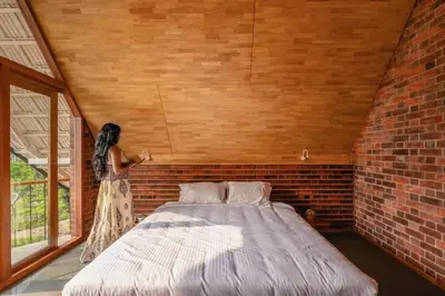 a woman standing next to a bed in a brick room at Bimal's Casa de Papel in Kadikkād