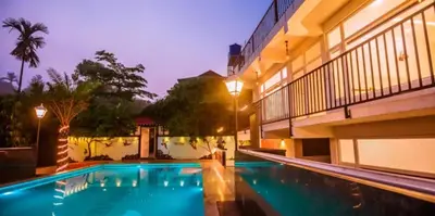 a swimming pool in front of a building at night at Wayanad Valentine Pool Resort in Sultan Bathery