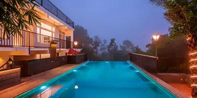 a swimming pool in front of a house at night at Wayanad Valentine Pool Resort in Sultan Bathery