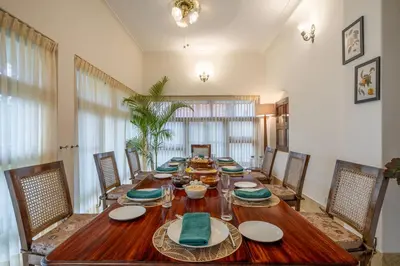 a dining room with a long wooden table and chairs at ama Stays & Trails Skanda , Coorg in Madikeri