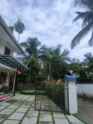 a fence in front of a house with palm trees at Chills homestay in Kalpetta