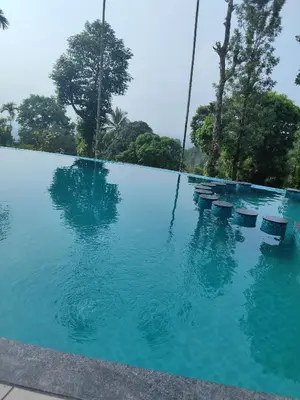 a pool of blue water with chairs in it at Chills homestay in Kalpetta