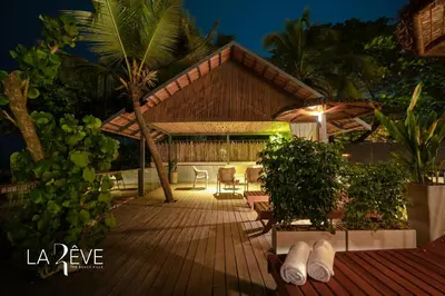 a house with a wooden deck at night at LA RÊVE The Beach Villa in Malappuram