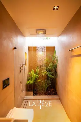a bathroom with a shower and a toilet with a plant at LA RÊVE The Beach Villa in Malappuram