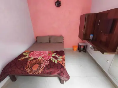 a small room with a bed in a pink wall at Ooty Prakash Residency in Ooty