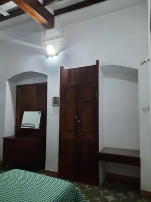 a bedroom with a bed and a cabinet and a mirror at Heritage Home, Hampe's in Mysore