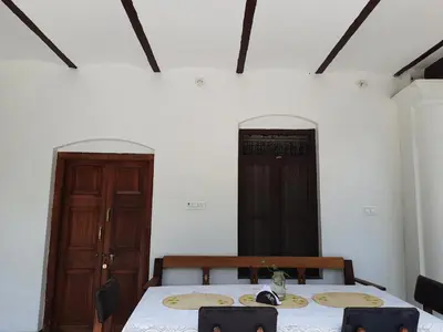 a dining room with a table and two doors at Heritage Home, Hampe's in Mysore