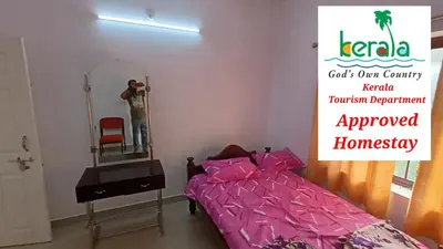 a man taking a picture of a bedroom with a bed and a mirror at Space villa Homestay in Irimbranallūr