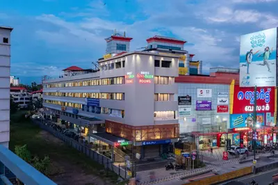 a tall white building with many signs in a city at Hotel Stay Bella Kozhikode in Kozhikode