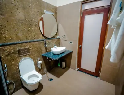a bathroom with a toilet and a sink and a mirror at The Odyssey Coorg in Madikeri