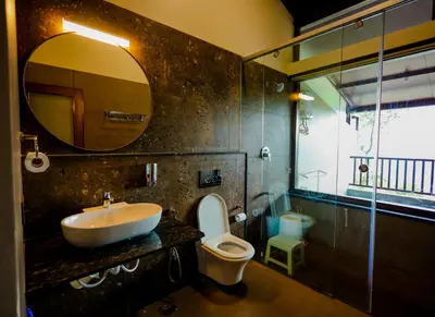 a bathroom with a sink and a toilet and a mirror at The Odyssey Coorg in Madikeri