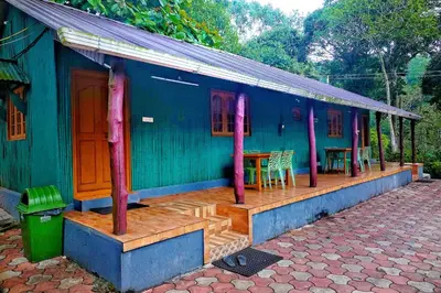 a blue house with a wooden porch and a table at Hill Valley Farm House in Nelliyampathy