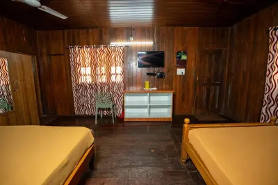 a bedroom with two beds and a tv and a desk at Hill Valley Farm House in Nelliyampathy