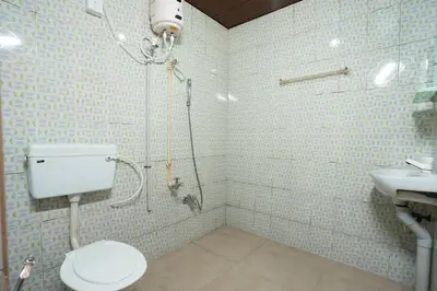 a bathroom with a shower and a toilet and a sink at Hill Valley Farm House in Nelliyampathy