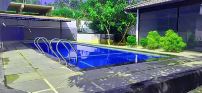 a swimming pool with chairs next to a house at Empire Single Bedroom Villa with Common Pool in Meenangadi