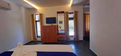 a bedroom with a bed and a dresser with a television at Empire Single Bedroom Villa with Common Pool in Meenangadi