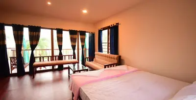a bedroom with a bed and a balcony with windows at Greens Vista Homestay Wayanad Near Natural Stream and Pool in Panamaram