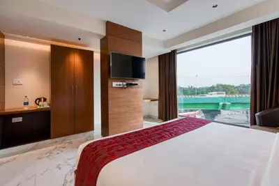 a bedroom with a large bed and a large window at Hotel Vilvah in Coimbatore