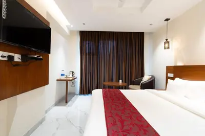 a hotel room with a bed and a tv at Hotel Vilvah in Coimbatore