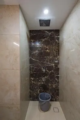 a bathroom with a shower with a bucket in it at Hotel Vilvah in Coimbatore