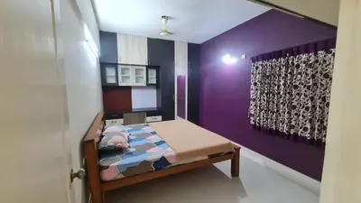 a bedroom with a bed with a purple wall at Kamalam 3BHK Villa 1AC and 2 Non AC Bedrooms in Coimbatore