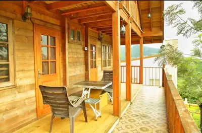 a porch of a cabin with a table and chairs at Joy Eco Woodhouse - 3 Bhk House in Ooty