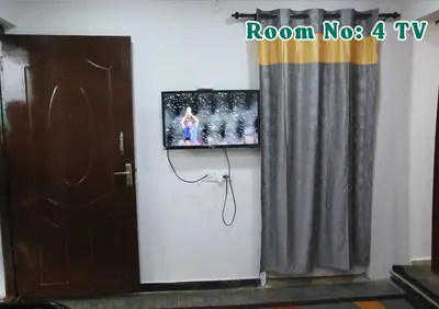 a tv on a wall next to a door with a curtain at Joy Eco Woodhouse - 3 Bhk House in Ooty