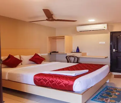 a bedroom with a large bed with red pillows at Hotel Vinayaga Tiruppur in Tiruppūr