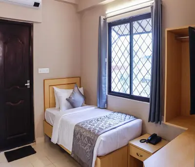 a small bedroom with a bed and a window at Hotel Vinayaga Tiruppur in Tiruppūr