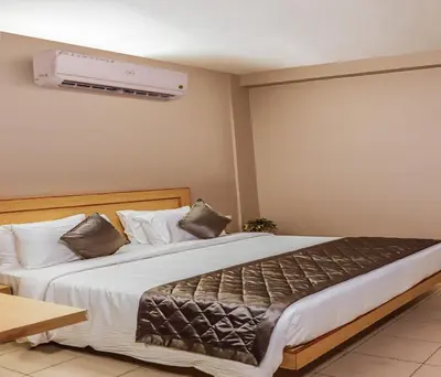 a bedroom with a large bed with white sheets at Hotel Vinayaga Tiruppur in Tiruppūr