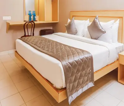 a bedroom with a large bed with white sheets at Hotel Vinayaga Tiruppur in Tiruppūr