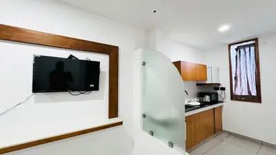 a room with a tv on a wall in a kitchen at Rose Garden at Rajagiri Hospital in Ernakulam