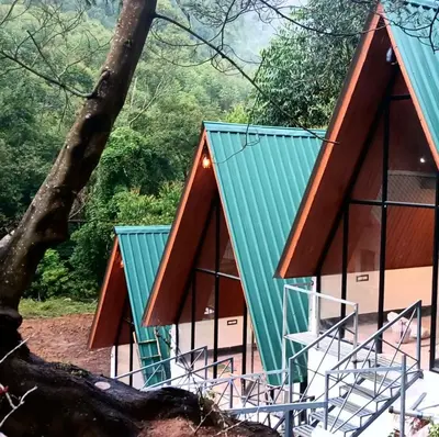 a pair of houses with green roofs at Vattavada Jungle Resort in Munnar