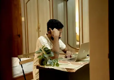 a man sitting at a table with a laptop computer at Palace Hostel by Borrbo in Mysore