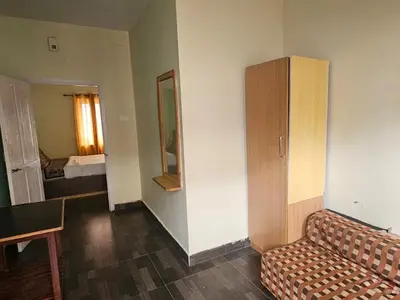 a room with a couch and a cabinet and a bedroom at Stay awhile in Ooty
